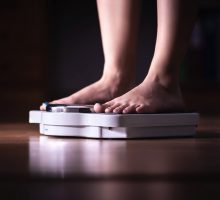 Woman weighing herself on a scale to see if new weight loss medicine is helping