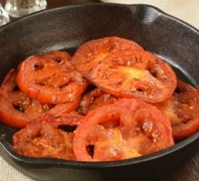 Closeup of fried tomatoes in a cast iron skillet