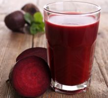Glass of beet juice with beets on wooden table