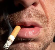 a closeup of a man smoking a dangling cigarette
