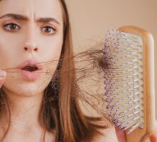 Woman is upset about hair loss because of hair on brush