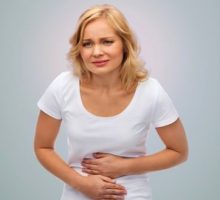 Woman with heartburn or a stomach ache holding her abdomen in pain