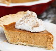 Slice of homemade pumpkin pie with whipped cream