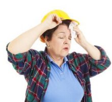 a female construction worker wiping her brow while having a hot flash, postmenopausal hormones
