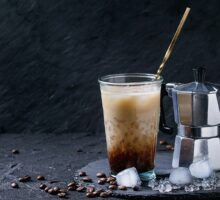 iced coffee with ice cubes next to espresso pot may help migraine headaches