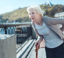 Older woman with a cane experiencing intense back pain