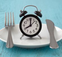empty plate with a clock indicating intermittent fasting or time-restricted eating