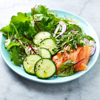 A low-carb mixed leaf salad with smoked salmon, spinach, cucumber and onions; eat to lower cholesterol; calm chronic inflammation