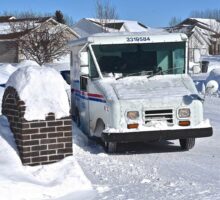 mail truck delivering mail to mail box covered with snow