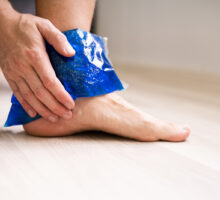 man applying ice gel back to sprained ankle