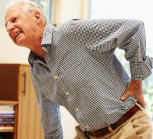 Senior man with backache holds his lower back
