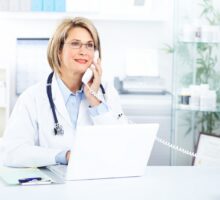 Doctor uses telephone and laptop for virtual visits
