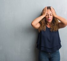 woman holding head suffering from recurrent migraines