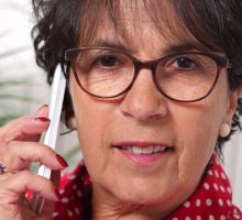 Mature woman with wrinkles around her eyes talking on a cell phone