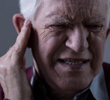 Old man suffering from tinnitus or ringing in the ear
