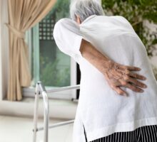 older woman with osteoporosis and back pain using a walker