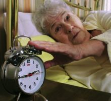 older woman with insomnia silencing her alarm clock