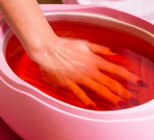 a woman using a hot wax soak for painful cracked fingertips & arthritis