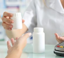 pharmacist hands selling medicines to a customer on a pharmacy desk; simple job description; refill prescriptions