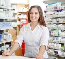 Portrait of female pharmacist standing at counter in pharmacy