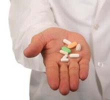 doctor in a lab coat with a handful of pills