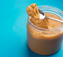 spoon full of peanut butter balanced on peanut butter jar