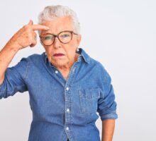 gray haired woman pointing to acne pimple