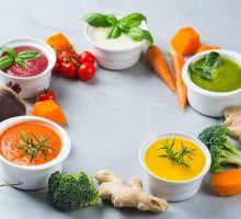 Five bowls of soup made with lots of veggies rich in carotenoids