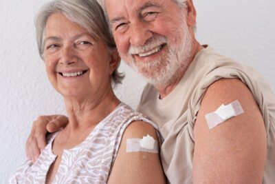 Smiling seniors showing off vaccinations