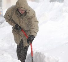 man in a parka shoveling a lot of snow