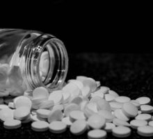 A aspirin bottle open and aspirin pills spilled out