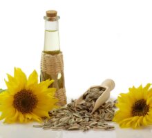 Bottle of vegetable oil on table with sunflowers and sunflower seeds