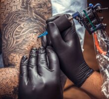 Tattoo artist working on a subjects arm with lots of tattoos