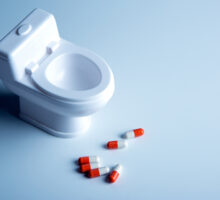 Miniature toilet bowl with red and white laxative pills