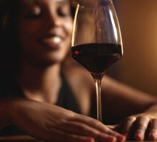 woman touching glass of red wine with both hands