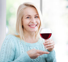 woman holds a glass of red wine