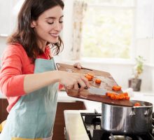 Woman cooking carrots in kitchen