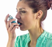 Woman looking away while using asthma inhaler