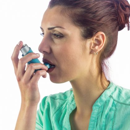 Woman looking away while using asthma inhaler