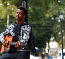 Young man singing and playing guitar outside