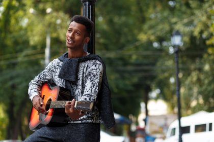 Young man singing and playing guitar outside