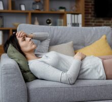 woman lying on a couch exhausted with long COVID