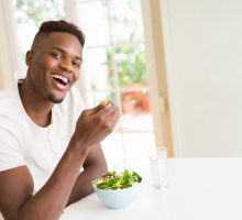 A young man eats salad for its health benefits
