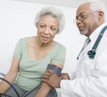 male doctor & female patient measuring her blood pressure