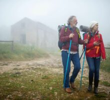Senior hikers walking together on a foggy mountain path.