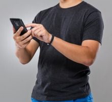 man wearing fitness tracker wristband using mobile phone