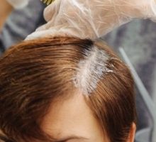 gray roots being dyed with hair dye at a salon