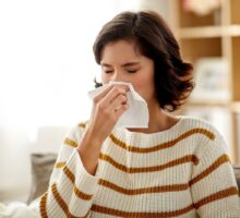 Woman with year-round allergies is blowing nose