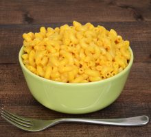 macaroni and cheese on wood table with a fork
