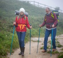 Older couple hiking with trekking poles on a mountain trail.